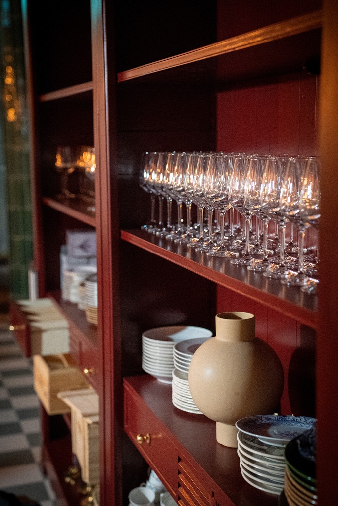 Interiören på Oss Emellan — vinröda hyllor med glas och porslin